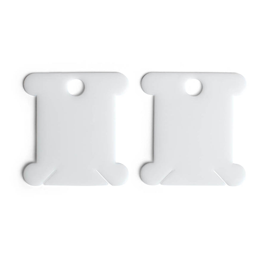 Two white plastic thread bobbins placed against a plain background.
plastic 
A pack of 30 white plastic thread bobbins, showing their classic flat shape with two secure notches at the bottom for thread management 
Thread Bobbins, Embroidery Floss Organizer, Cross Stitch Thread Holders, White Plastic Bobbins 30 pack, Floss Winding Tools