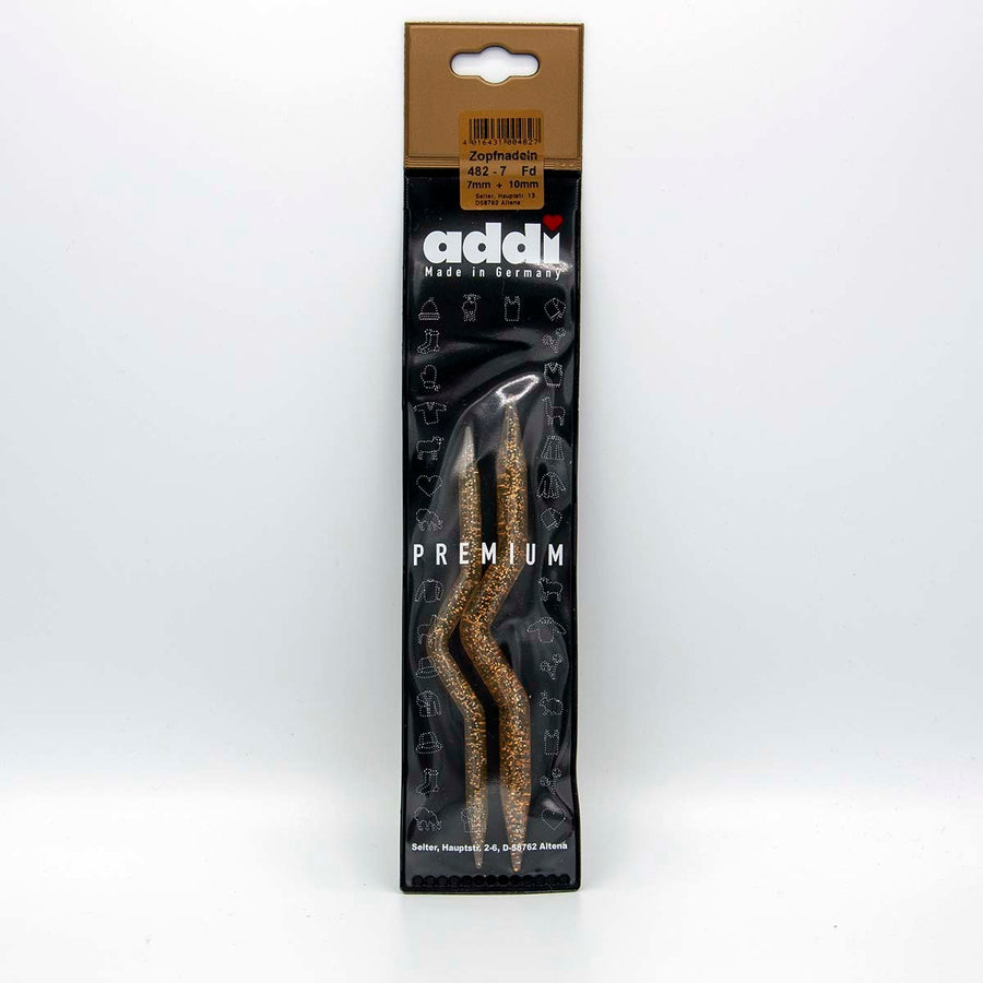 A set of two high-quality Addi cable stitch holders in a fun gold glitter finish. The set includes one 7.0mm and one 10.0mm holder, each featuring a 'crank' or 'U' shape in the middle to securely hold thick yarn stitches while knitting cable patterns.