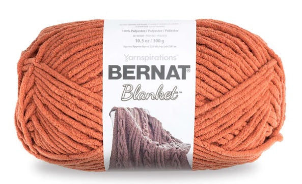 Close-up of Bernat Blanket yarn showing the plush velvety texture; a hypoallergenic and machine-washable yarn ideal for baby blankets and home decor. In pumpkin orange colour