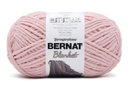 Close-up of Bernat Blanket yarn showing the plush velvety texture; a hypoallergenic and machine-washable yarn ideal for baby blankets and home decor. In light pink colour