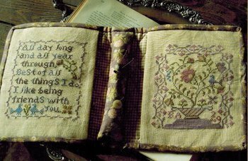 Decorative book with embroidered text and patterns on a wooden surface. Cross stitch pattern by Blackbird design.