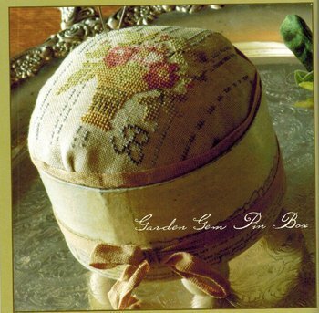 Decorative sewing pin box with floral embroidery and a ribbon on a textured surface. Garden Gem Pin Box by Blackbird designs.