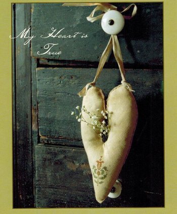 Heart-shaped fabric decorations with a button and ribbon on a wooden background with text 'My Heart is True'.