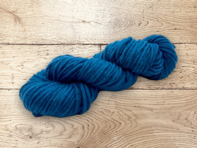 Blue yarn skein on a wooden surface. 100% Uruguayan Corriedale yarn for sale