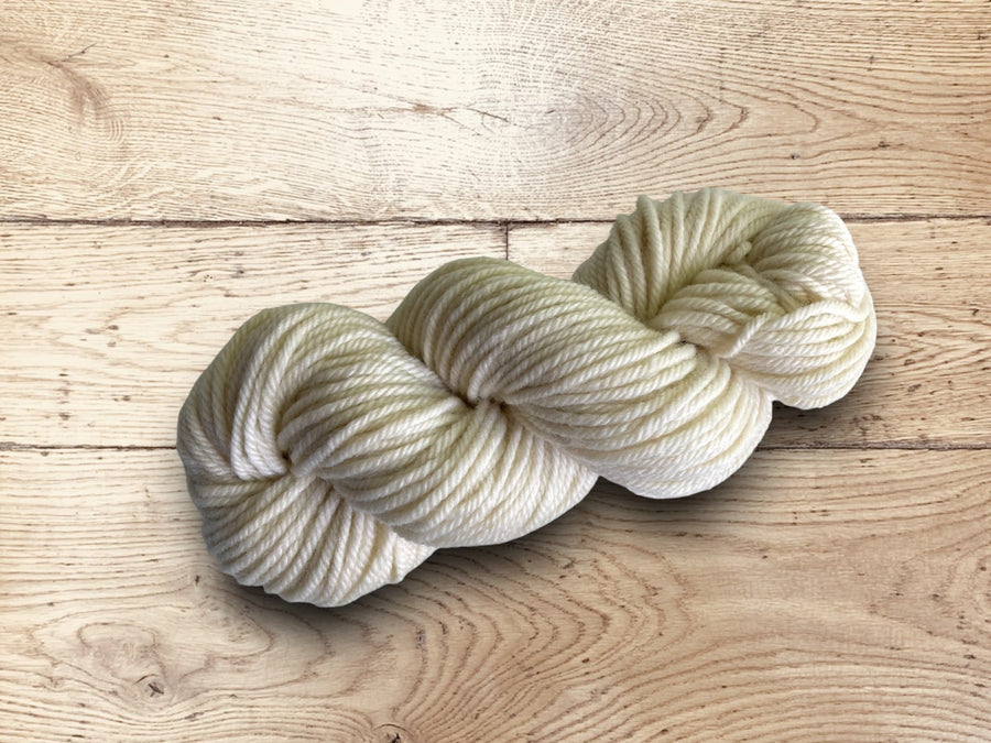 Chunky cream-colored yarn on a wooden surface.100% Uruguayan Corriedale chunky yarn for sale.
