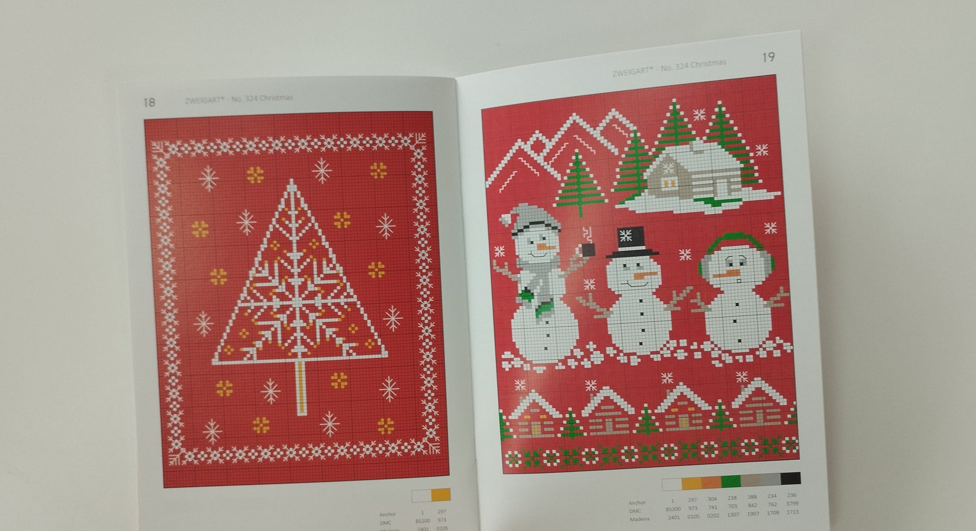 Two printed Christmas-themed cross-stitch patterns showing a Christmas Tree Motif and snowman