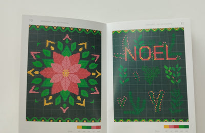 Open book with cross-stitch patterns, one featuring 'NOEL' and a poinsettia design.