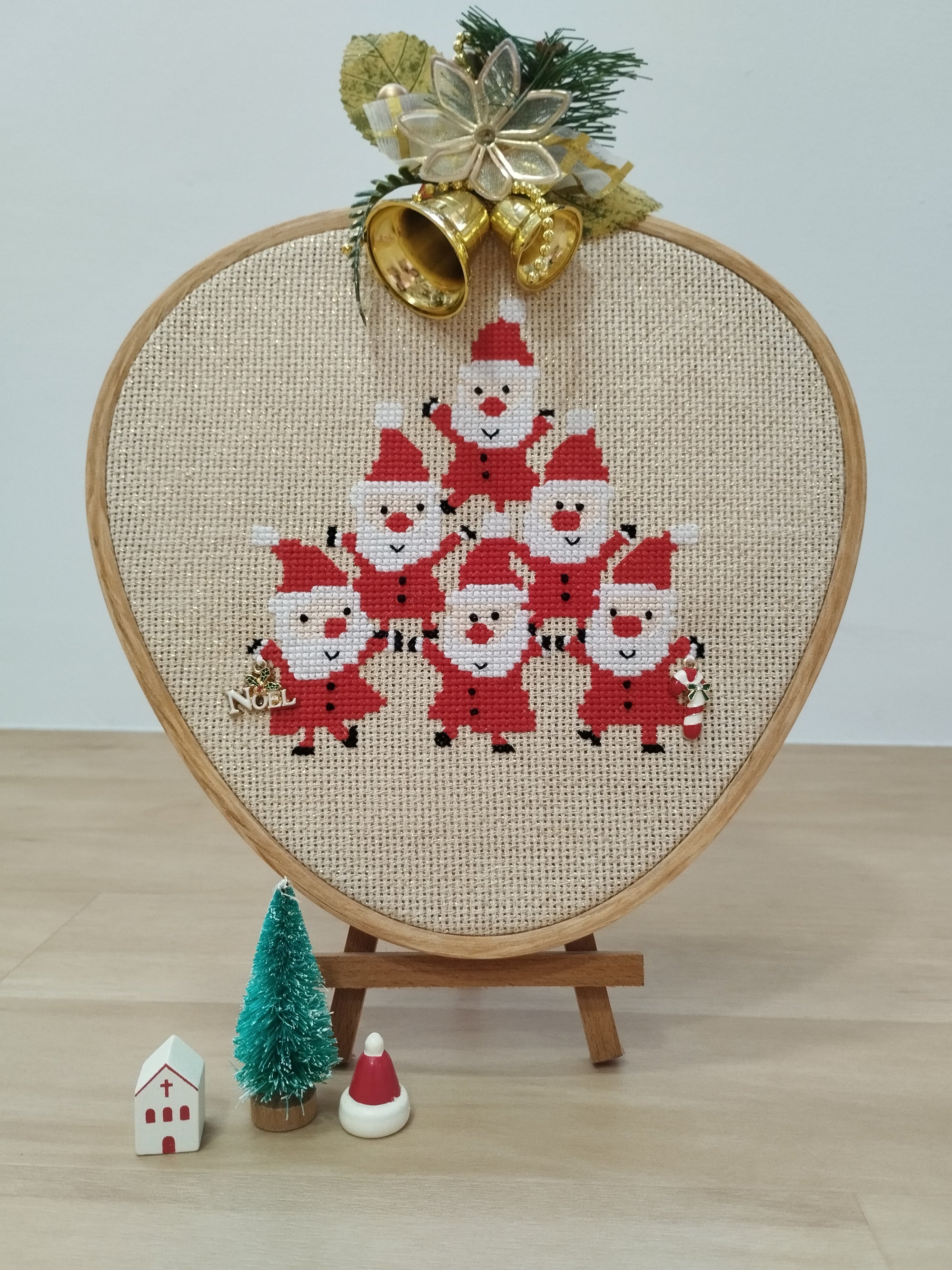 Embroidery hoop with a Christmas-themed design of Santa Claus on a wooden stand. Free Christmas cross stitch pattern. Finishing ideas