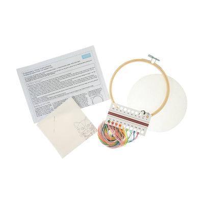 Complete Trimits DIY embroidery kit including a wooden hoop, pre-printed cat design fabric, colorful embroidery threads, needle, and instructions.