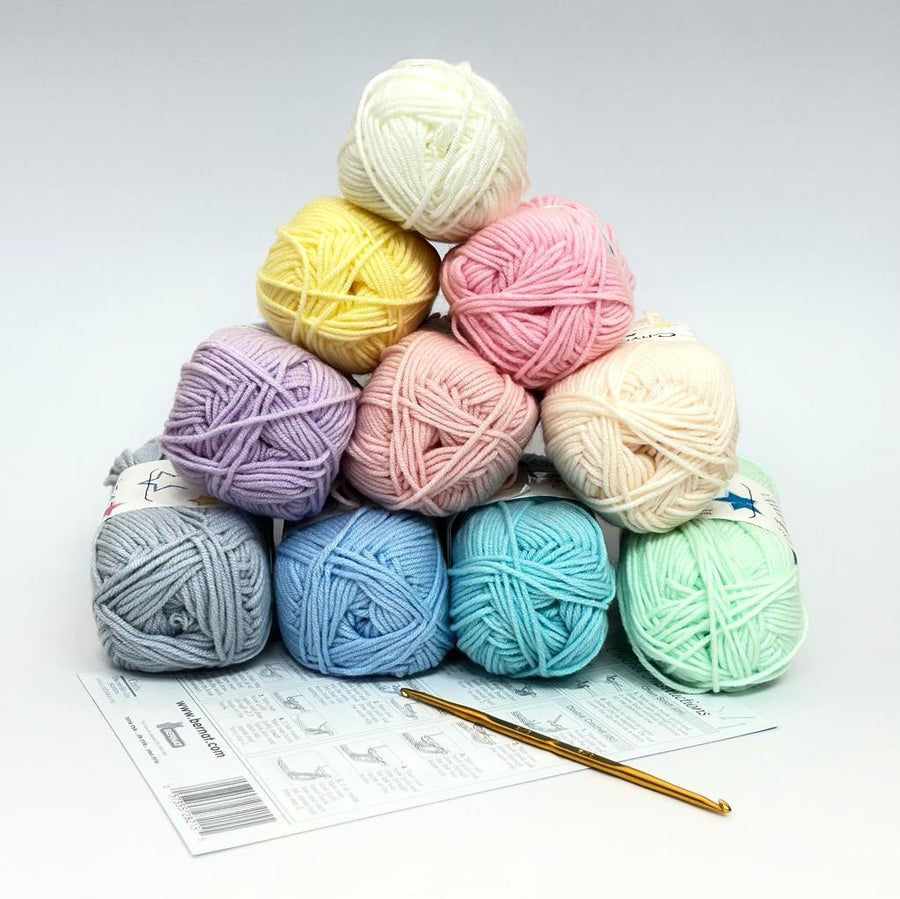 A collection of pastel colored yarns arranged in a pyramid shape with a crochet hook and an instruction sheet in the front.