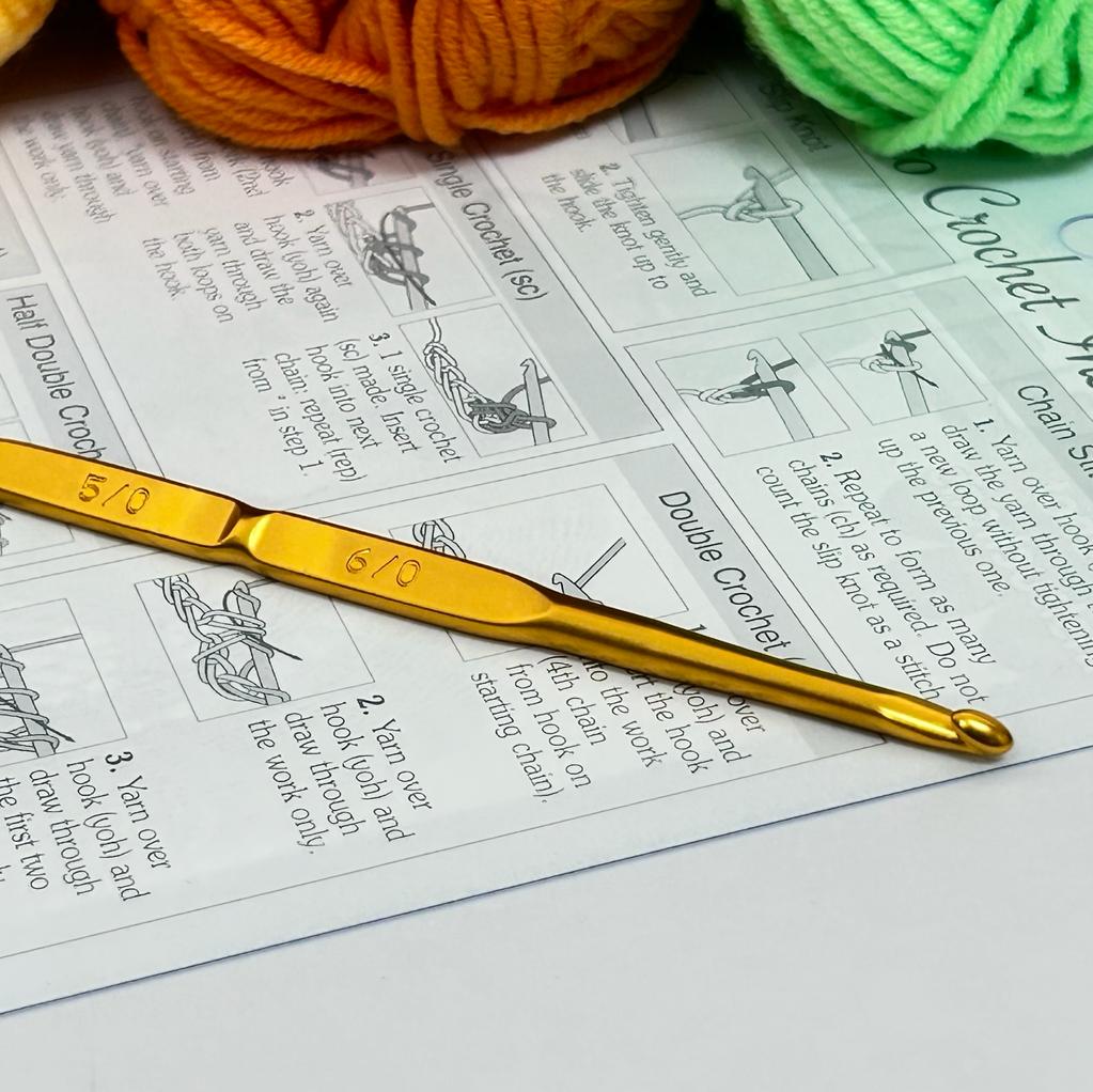 A vibrant and cheerful rainbow crochet starter kit featuring nine 50g balls of 100% acrylic yarn in a full spectrum of colors, including bright red, sunny yellow, deep blue, and vivid purple. The kit includes a premium Japanese Tulip double-sided crochet hook (3.0mm/3.5mm) and an English instruction guide, presented as a perfect gift set for new crafters.