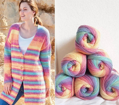 Woman wearing a colorful striped cardigan next to three skeins of multicolored yarn.