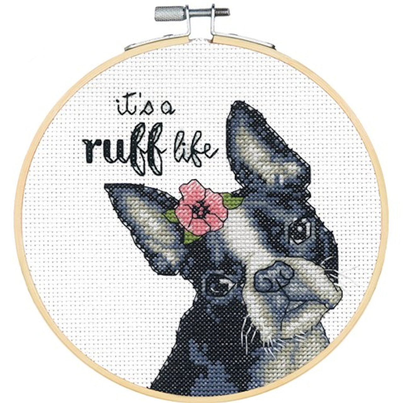 A beginner-friendly Dimensions cross-stitch kit titled 'Ruff Life.' The design features a cute black and white puppy with a pink flower on its head and the punny phrase 'it's a ruff life' stitched above. The kit includes 14-count white Aida fabric, a 6-inch bamboo hoop, pre-sorted thread, and a needle