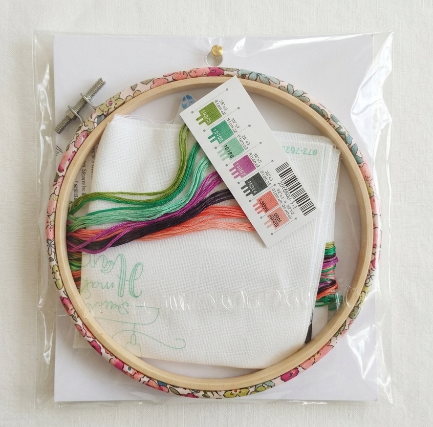 Embroidery hoop with colorful thread and a label on a white background