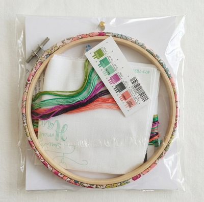 Embroidery hoop with colorful thread and a label on a white background
