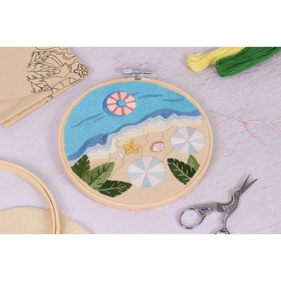 Beach View Embroidery Kit
An embroidery hoop kit with a beach-themed design, including a bamboo hoop, stranded embroidery threads, a metal needle, and felt backing.

The Trimits Beach View embroidery kit featuring a finished coastal scene with waves, sand, sea shells and palm tree leaves inside a bamboo hoop