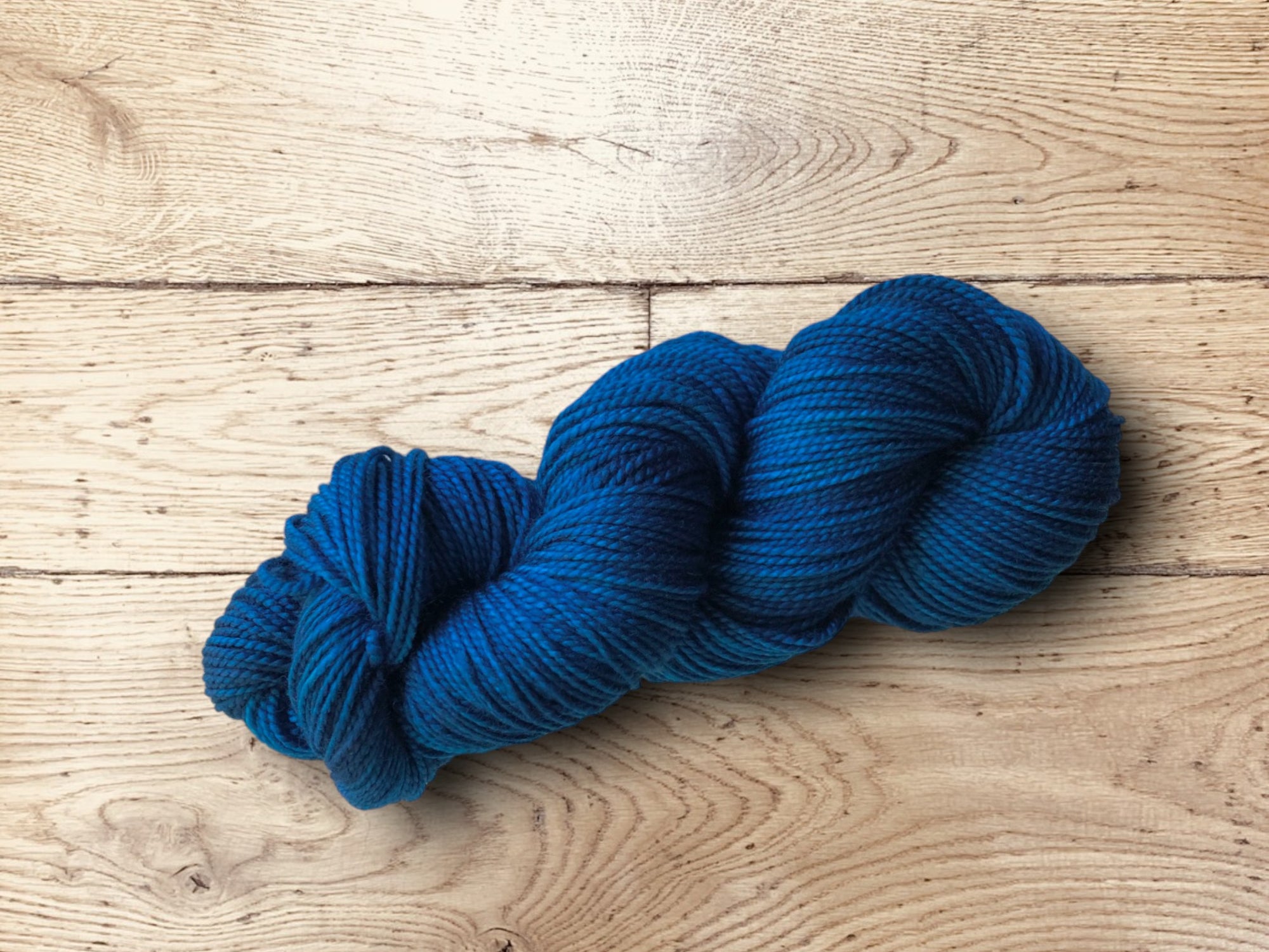 Dark Blue skein of yarn on a wooden surface. Sami Yarn by Manos del Uruguay for Sale.