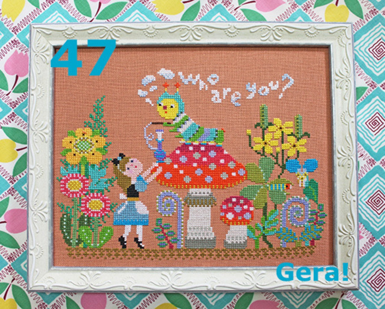 A professional-grade counted cross-stitch chart booklet by GERA! designed by Kyoko Maruoka, titled 'Alice Meets the Caterpillar.' The high-definition cover reveals a whimsical, storybook-style scene of Alice standing before the caterpillar perched atop a mushroom, rendered in a sophisticated, nostalgic pointillism aesthetic. The technical grid layout measures 141 stitches wide by 103 stitches high, capturing intricate Wonderland foliage, surreal smoke trails, and delicate character details.