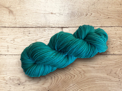 Turquoise skein of yarn on a wooden surface. 100% Luxury Superwash Merino for sale