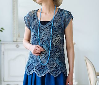 A model wearing a fashionable crocheted layered vest and a bright, summer necklace.
