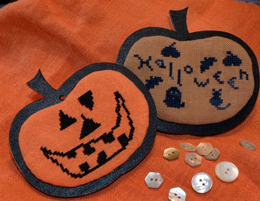 A professional-grade counted needlework chart package from Kelmscott Designs titled 'Pumpkin, Pumpkin.' The high-definition product features a boutique primitive folk art cross-stitch pattern alongside an exclusive, custom hand-painted wooden pumpkin shape designed to be mounted onto the finished stitching. The kit is an artisanal package containing the template and detailed step-by-step structural finishing instructions.