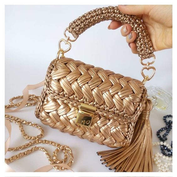 "A chic handmade metallic gold clutch bag crocheted with Tyanuchka, showcasing its lightweight and high-fashion appearance