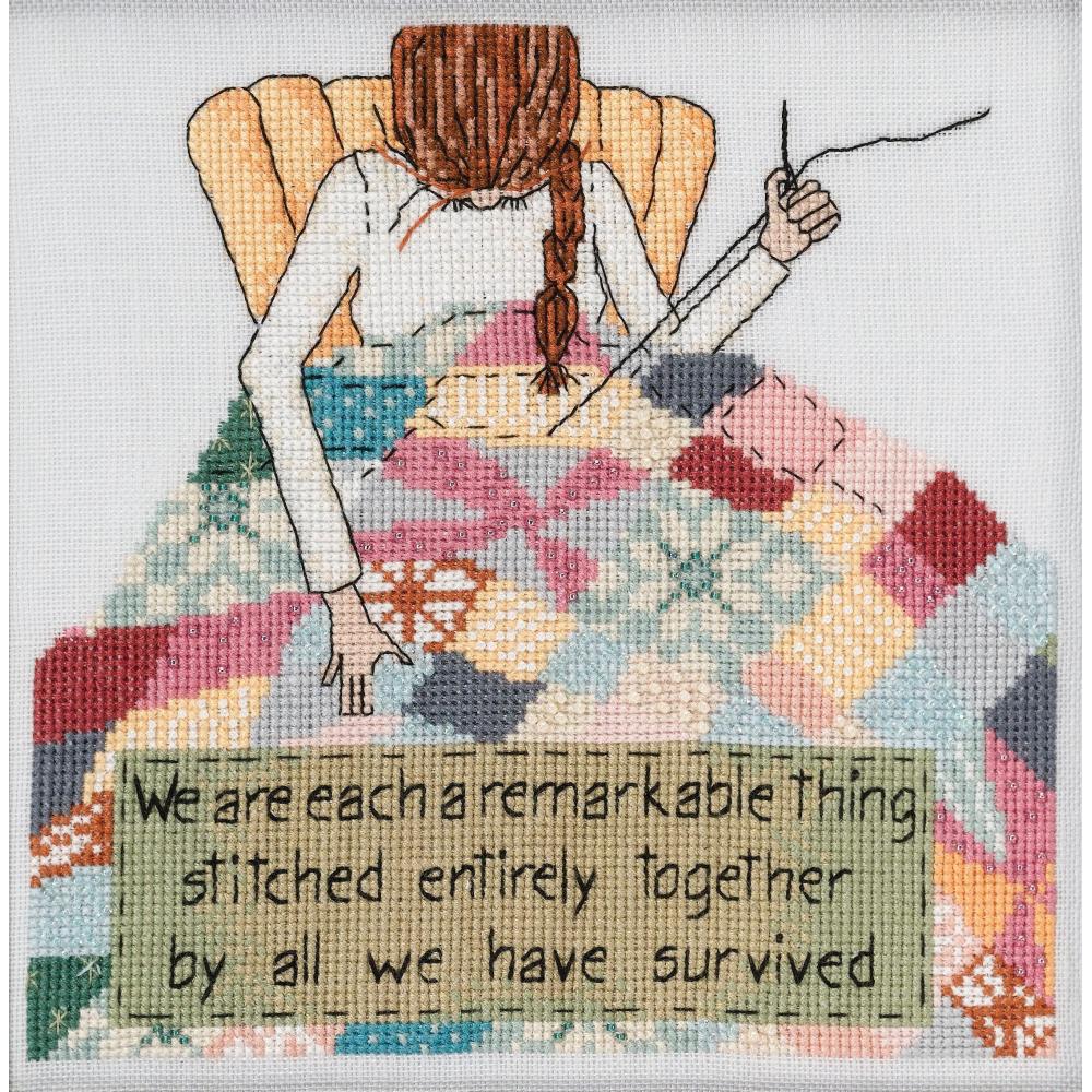 A cross stitch kit depicting a woman seated, surrounded by colorful patchwork fabric, with a humorous quote about stitching. Kit by mill hill USA