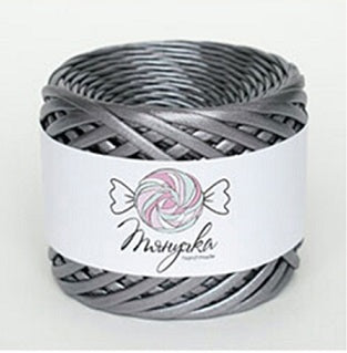 A spool of metallic Nickle silver yarn with a label that has a heart and wings graphic on it, set against a blurred bokeh background.