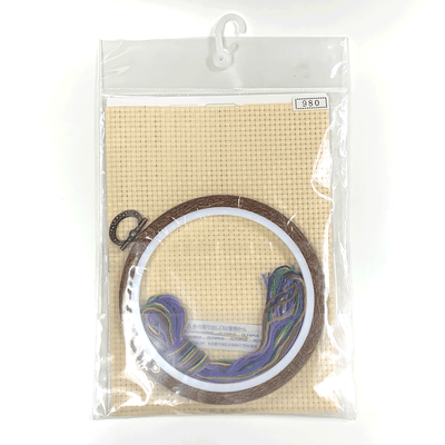 Detailed flat-lay of the Olympus kit: beige Java cross medium-eye cloth, vibrant stranded thread, tapestry needle, and a wood-tone fashionable display hoop