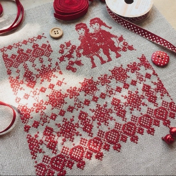 A professional-grade Christmas cross-stitch kit by designer Perrette Samoiloff. The high-definition design features a whimsical and delicate arrangement of red lace-like geometric patterns paired with classic holly leaves and berries. The artwork is contemporary and elegant, embodying a sophisticated holiday aesthetic
