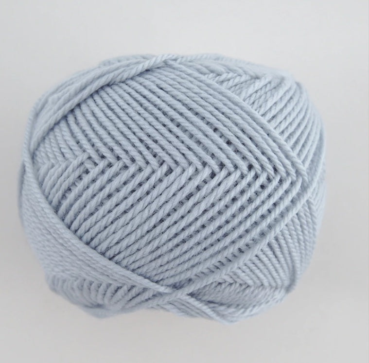 A 30g skein of Pierrot Fine Merino yarn in a soft matte finish, showing the delicate, tightly twisted 100% extra fine merino wool in frosty blue colour