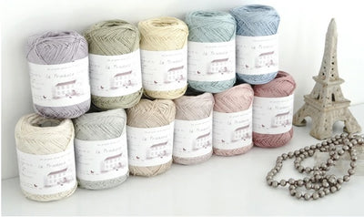 A collection of Pierrot Julien Silk Yarn skeins in various shades, displayed alongside a decorative item resembling a Eiffel Tower model. Pierrot Julien Silk Yarn, 100% Silk Knitting Yarn, Japanese Silk Fiber, Luxury Crochet Silk, Pierrot Yarn Singapore