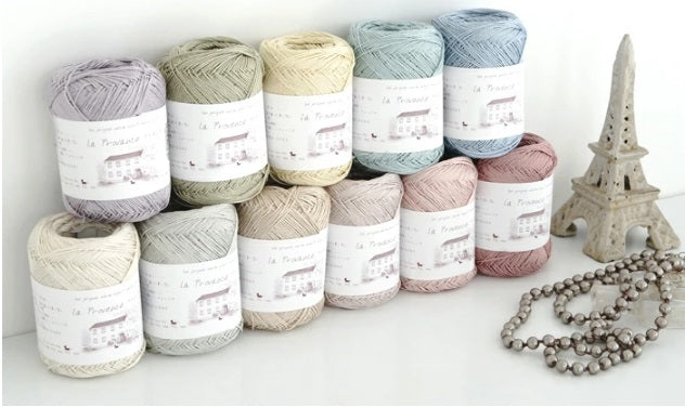 A collection of Pierrot Julien Silk Yarn skeins in various shades, displayed alongside a decorative item resembling a Eiffel Tower model. Pierrot Julien Silk Yarn, 100% Silk Knitting Yarn, Japanese Silk Fiber, Luxury Crochet Silk, Pierrot Yarn Singapore