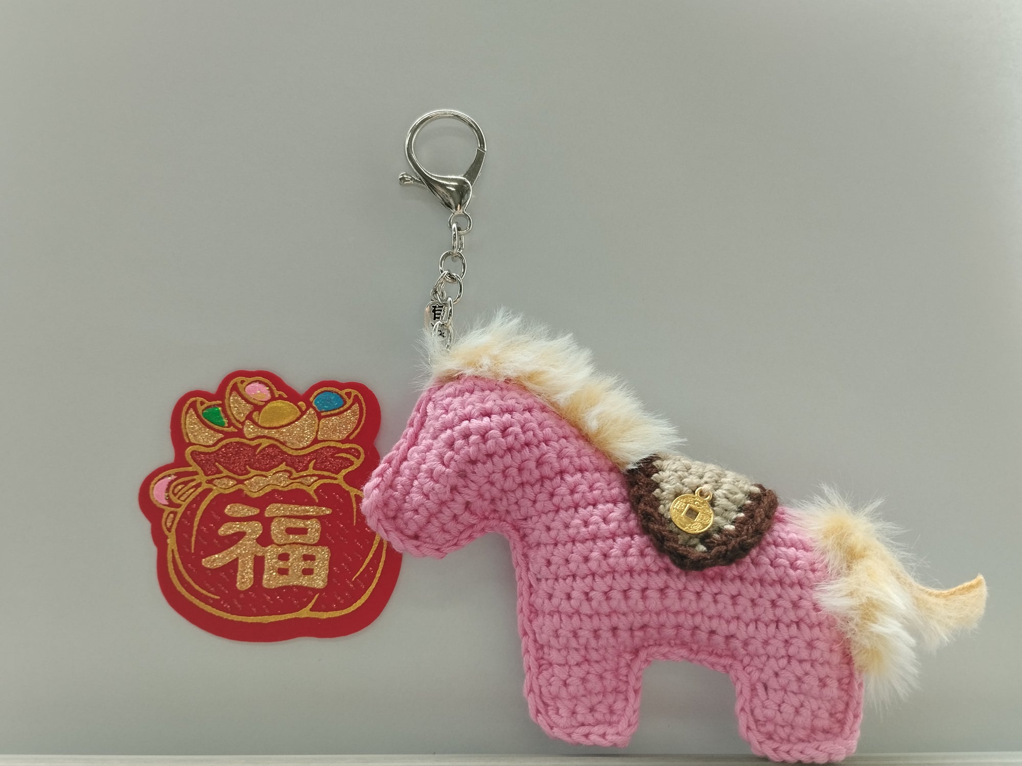 For Sale Pink crochet horse keychain with a decorative patch on a light gray background. hand crochet in Singapore artisan made. Small craft shop hand made item for sale.