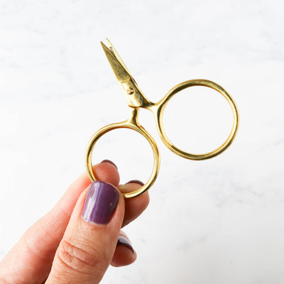 A pair of Putford Primitive miniature scissors featuring distinctively large circular finger holes and short, sharp blades. The scissors are shown in three vintage-inspired colors, highlighting their compact 2.5-inch size and handcrafted 'primitive' aesthetic, perfect for precise thread snipping