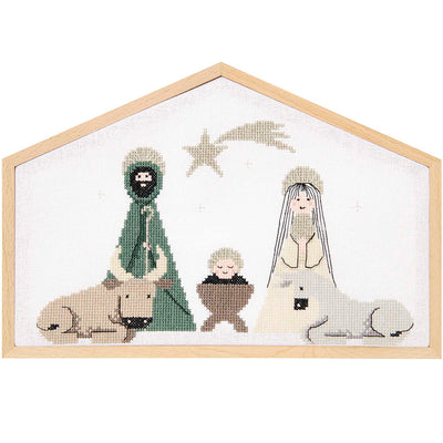 Cross stitch kit depicting a nativity scene with various characters and a dog, framed in a light-colored wooden house frame.