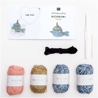 A top-down view of the complete Narwhal kit contents, including shades of blue and metallic gold Ricorumi 100% cotton yarn, a crochet hook, safety eyes, and a needle