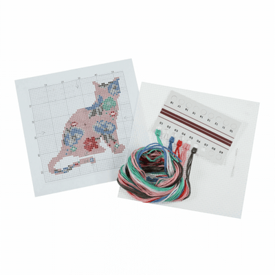 Flat-lay of the beginner-friendly cat cross stitch kit, highlighting the organized threads, a plastic safety needle, and the clear, color-coded pattern chart.