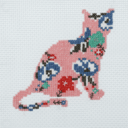 Cross stitch kit depicting a colorful cat design on white aida cloth with embroidery thread.