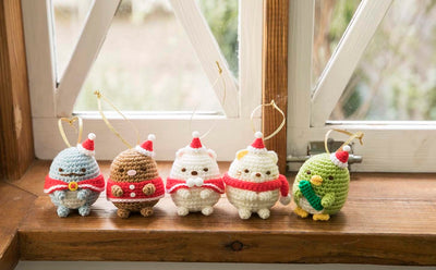 A display of finished Sumikko Gurashi crochet characters arranged in a cute 'corner' scene with felt decorations. All wearing Christmas scarf and Christmas hats