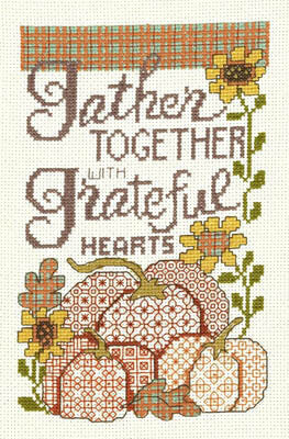 A cross stitch kit depicting a colorful autumn-themed design with the text 'Gather together with Grateful hearts' and floral patterns, including sunflowers and pumpkins.