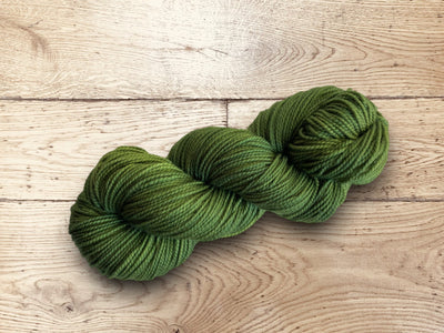 Olive green yarn on a wooden surface. 100% Superwash Merino worsted weight for sale