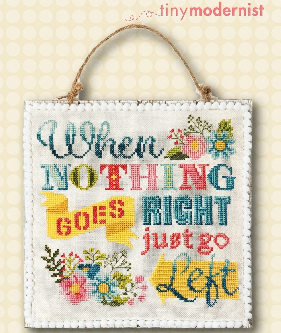 A professional-grade cross-stitch kit by Tiny Modernist titled 'Just Go Left.' The high-definition design features a modern, colorful tortoise with a patterned shell, accompanied by the soulful text 'Just Go Left.' The artwork style is clean and vibrant, perfect for a modern home decor project."