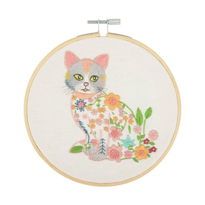 Trimits Cat Embroidery Hoop Kit featuring a charming  white cat design with simple, elegant floral accents on a neutral fabric background.
Embroidery hoop kit depicting a cat with floral patterns on a beige background, completed and framed.