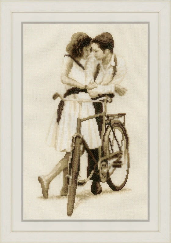 Cross-stitched depiction of a couple on a bicycle, framed as a picture.

Vervaco Couple with Bicycle Kit.
The Vervaco 'Couple with Bicycle' cross-stitch kit showing a romantic couple on a bike with soft, pastel-toned threads.