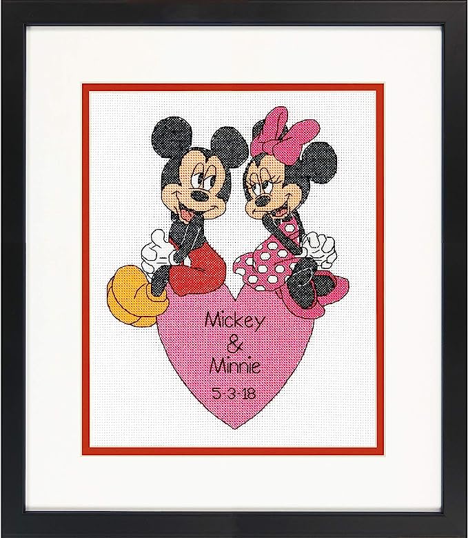 Cross-stitched picture of Mickey and Minnie Mouse on a heart with personalized text, framed in black.
