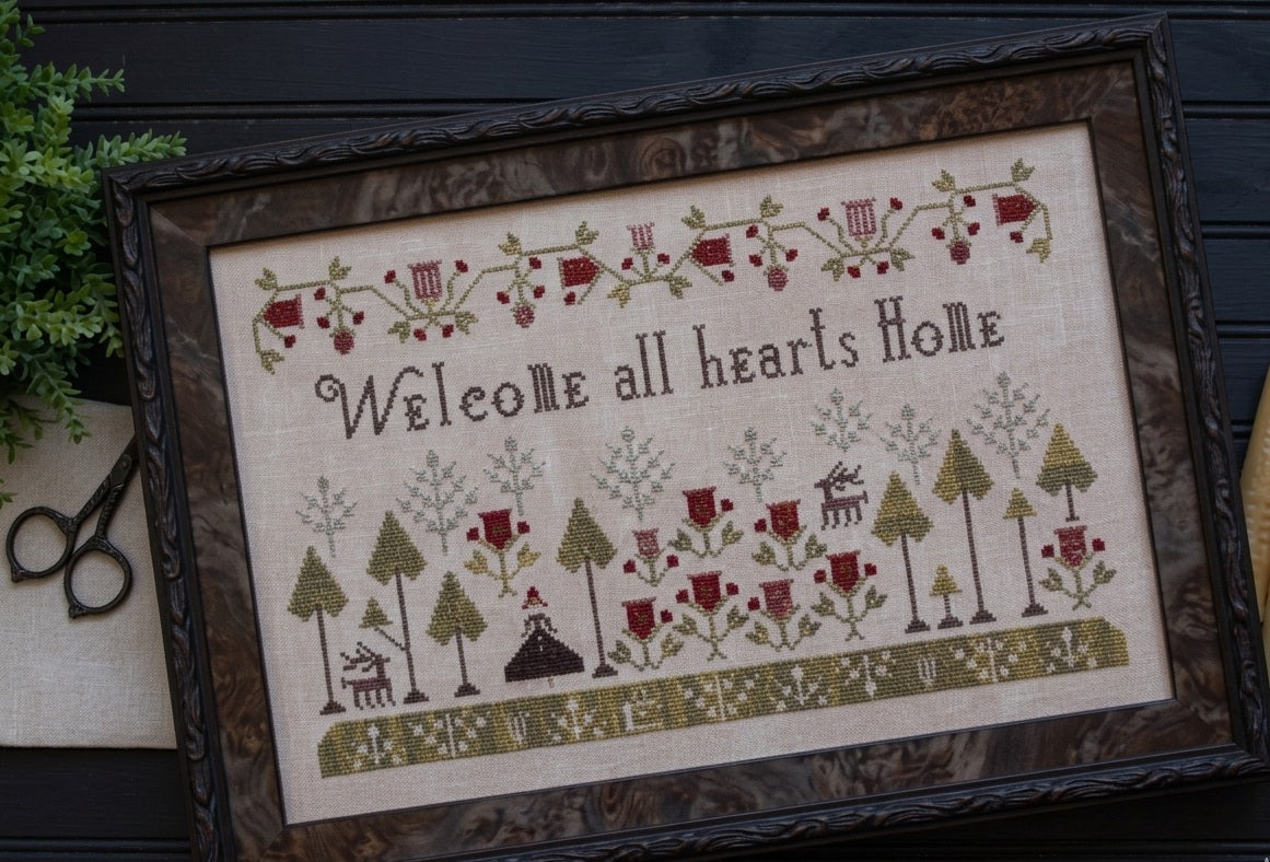A professional cross-stitch chart for a large-scale traditional sampler titled 'Welcome All Hearts Home.' The high-definition design features the central welcoming text surrounded by an intricate arrangement of folk-art motifs, such as houses, trees, birds, and decorative heart borders.