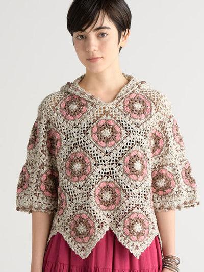 Woman wearing a crocheted poncho with pink floral patterns on a white background