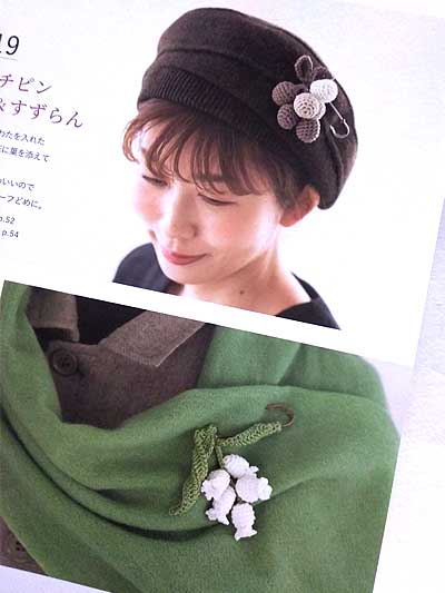 model showing crocheted lily of the valley jewelry on shawl and wearing crochet accessories on hat.