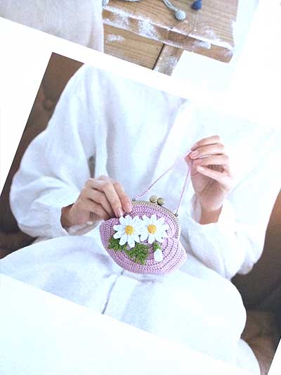 Model carrying a crocheted purse with metal clasp with crocheted daisy and leaves on it